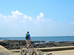 Patrick on the shoreline over black volcanic rocks.