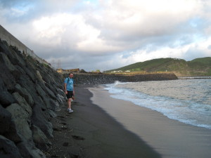 Patrick on the narrow strip of dry sand on the black sand beach. The tall cliffs behind him are the crater where we hiked last week!